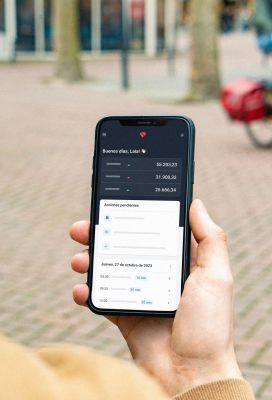Una persona sosteniendo un movil donde se ve la pantalla de Holded